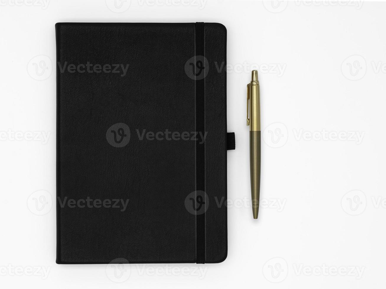 Black notebook closed and gold pen next to it on white background photo