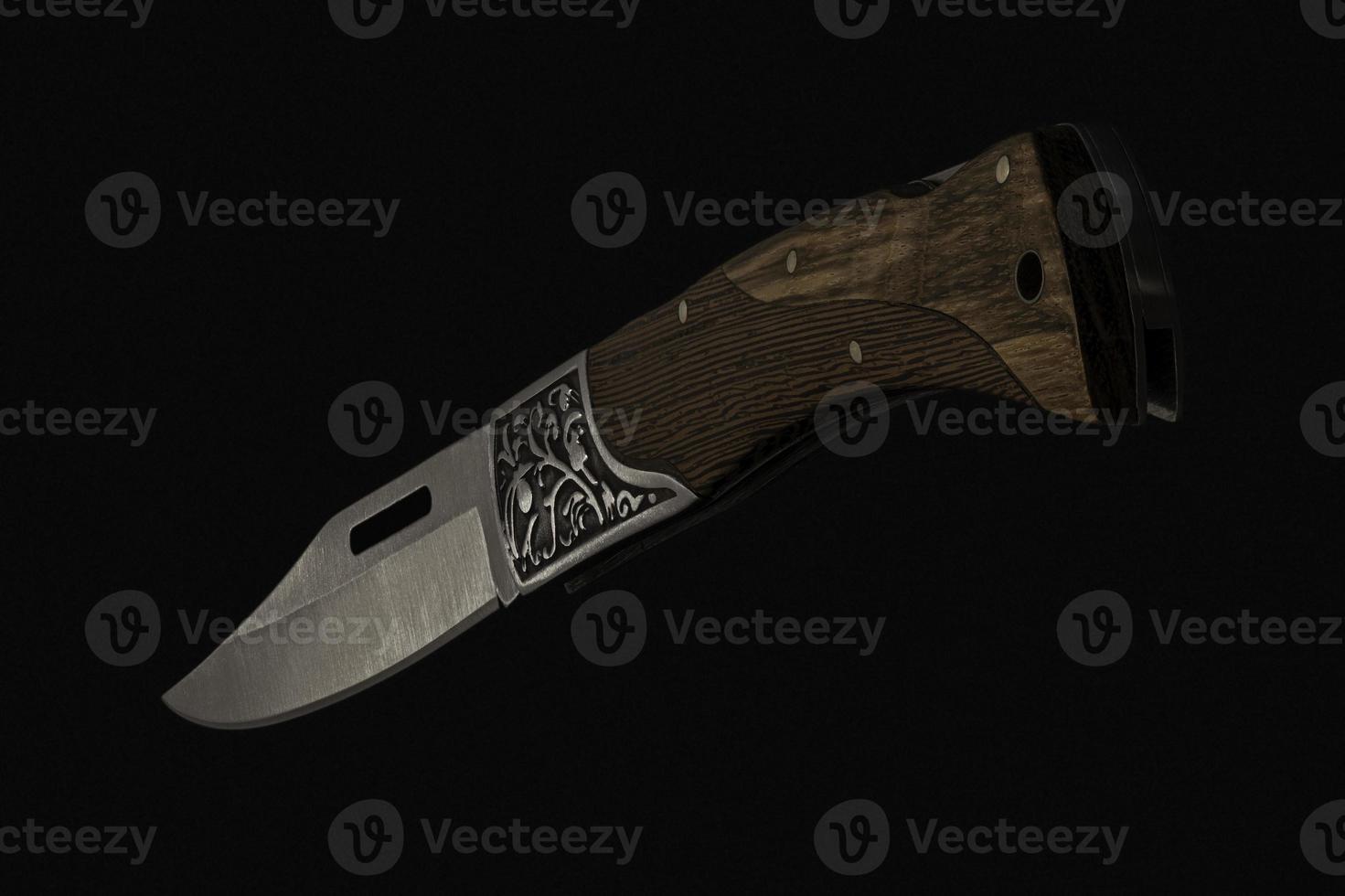 close-up of foldable handmade knife with sharp blade, wooden handle on black background made in Cambodia photo