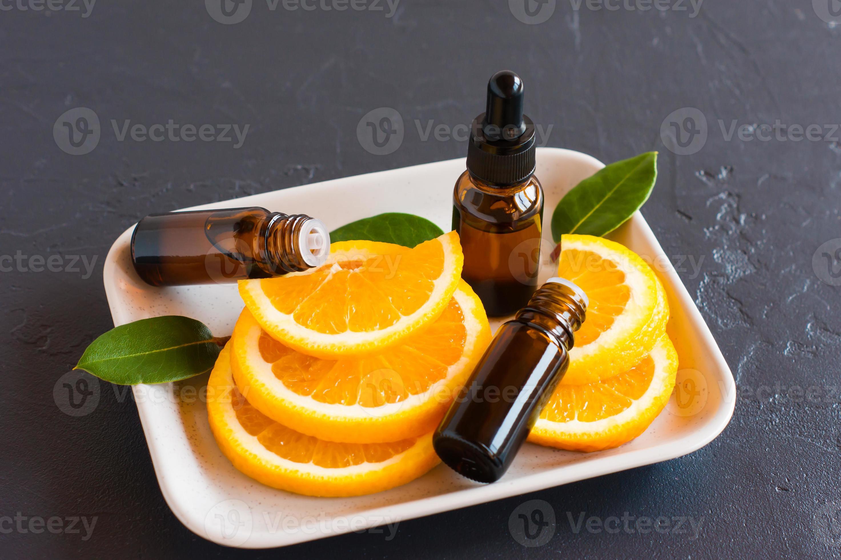 three bottles of brown glass with orange essential oil on a ceramic