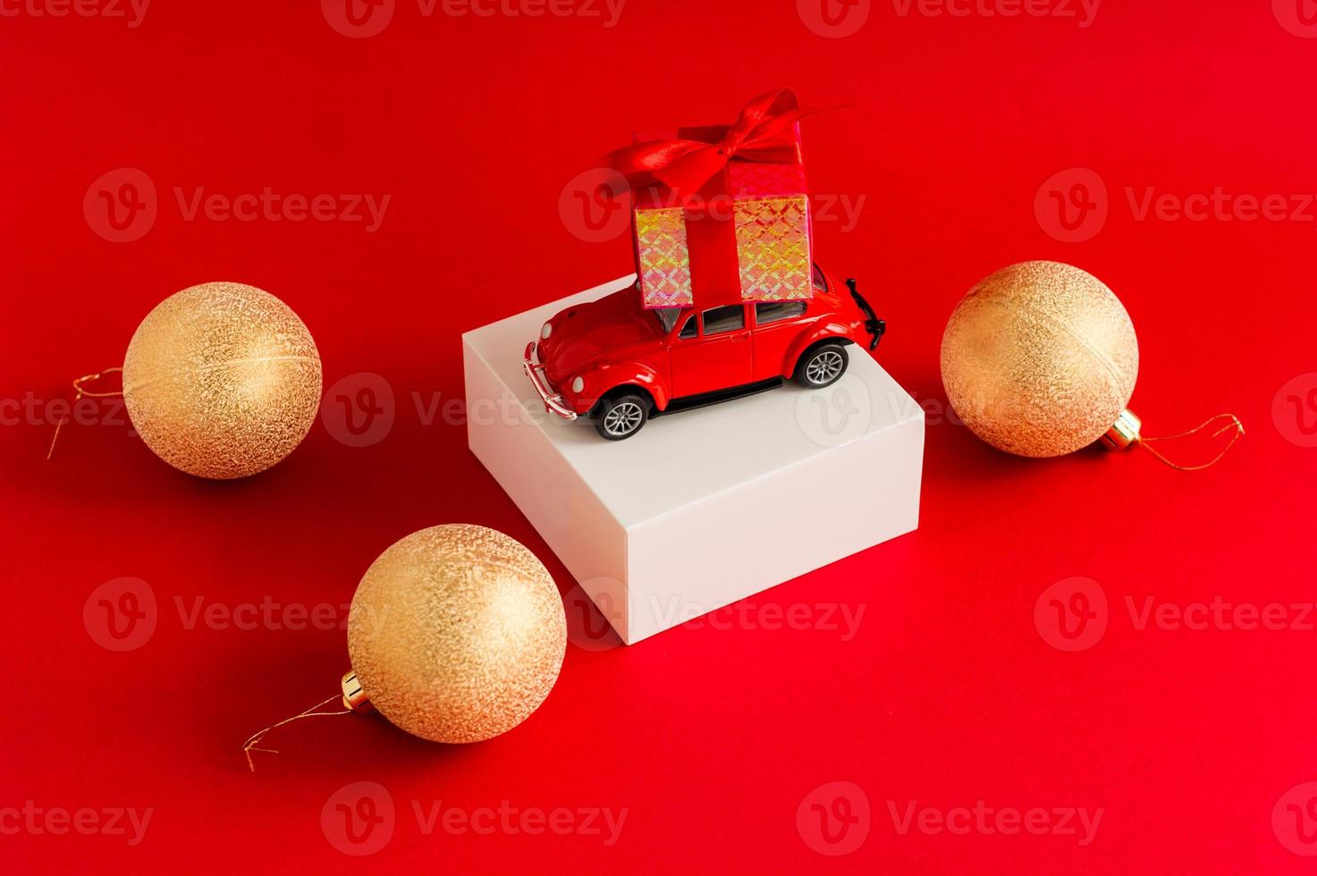 Red retro car with a gift box on the roof on a white pouill and a red background with a new-fashion ball. a copy of the space. photo