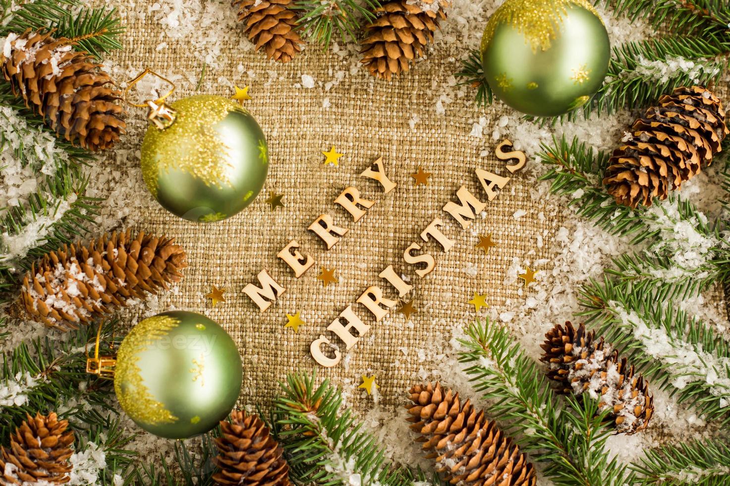 Christmas traditional background with Christmas balls, cones and branches of spruce. laid out wooden letters, with a wish for a Merry Christmas. photo