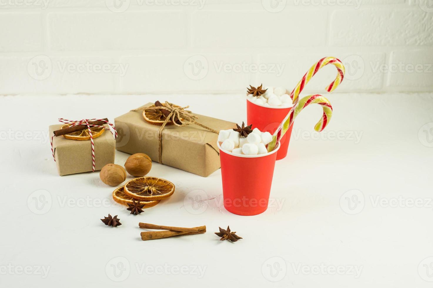 Christmas composition on a white background. gift boxes made of kraft paper and two paper red cups with cocoa and marshmallow. nuts, anise stars. photo