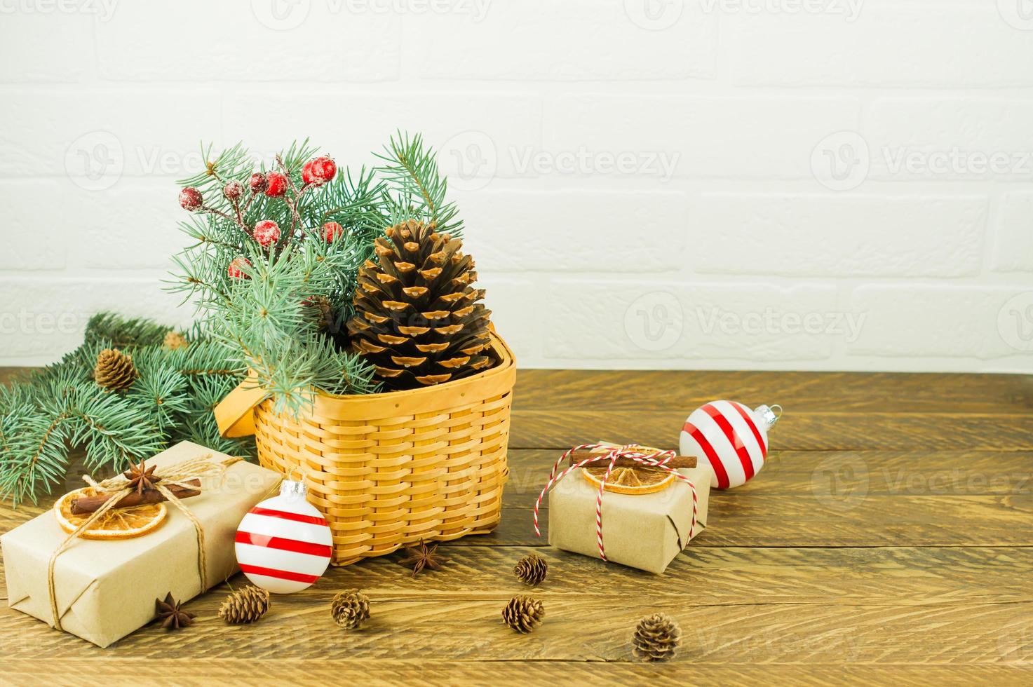 decoración festiva para la casa en navidad. cesta de mimbre con ramas de  abeto y bayas, cono de cedro y cajas de regalo sobre una mesa de madera.  12874283 Foto de stock