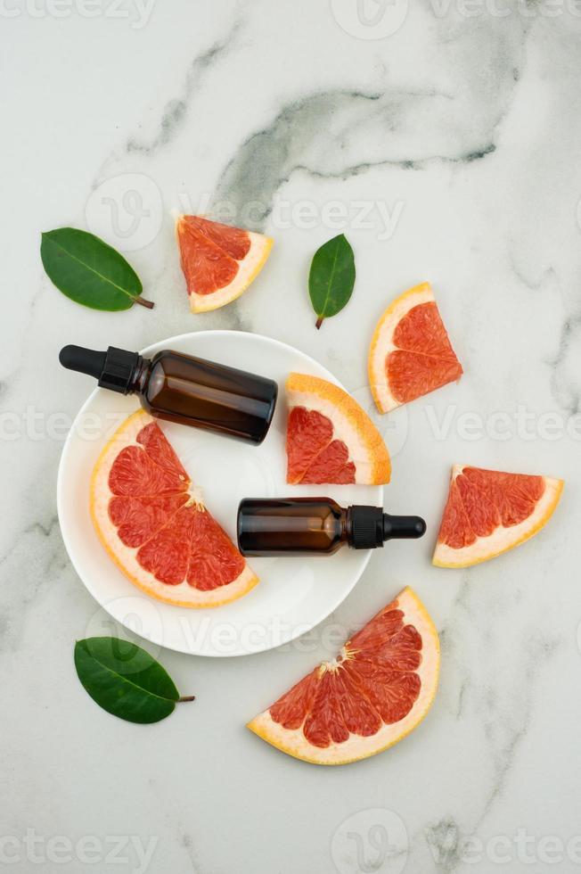 top view of a white plate with two bottles-dropper with grapefruit oil and fruit slices. moisturizing, aromatherapy, anti-stres effect. photo