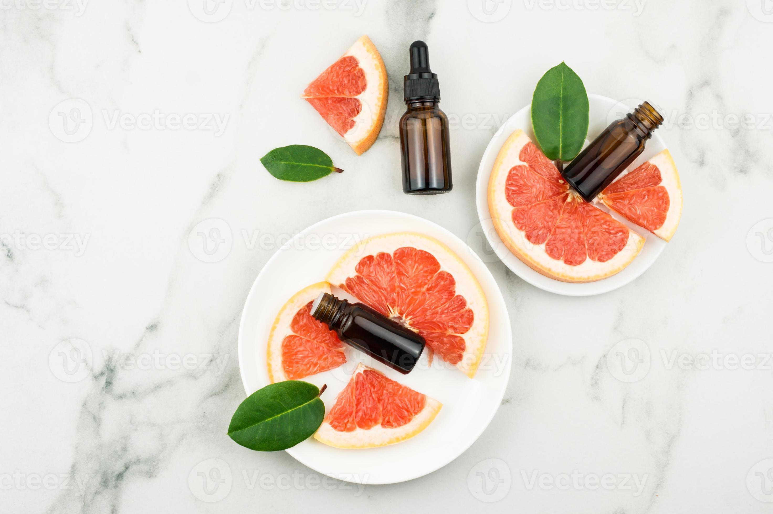 cosmetic and medical bottles with grapefruit extract on white plates