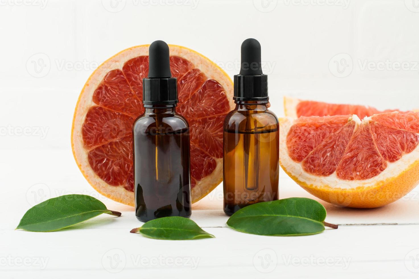 two bottles of droppers with cosmetic grapefruit oil or facial serum against the background of fresh grapefruit fruit. a natural concept of self-care. photo