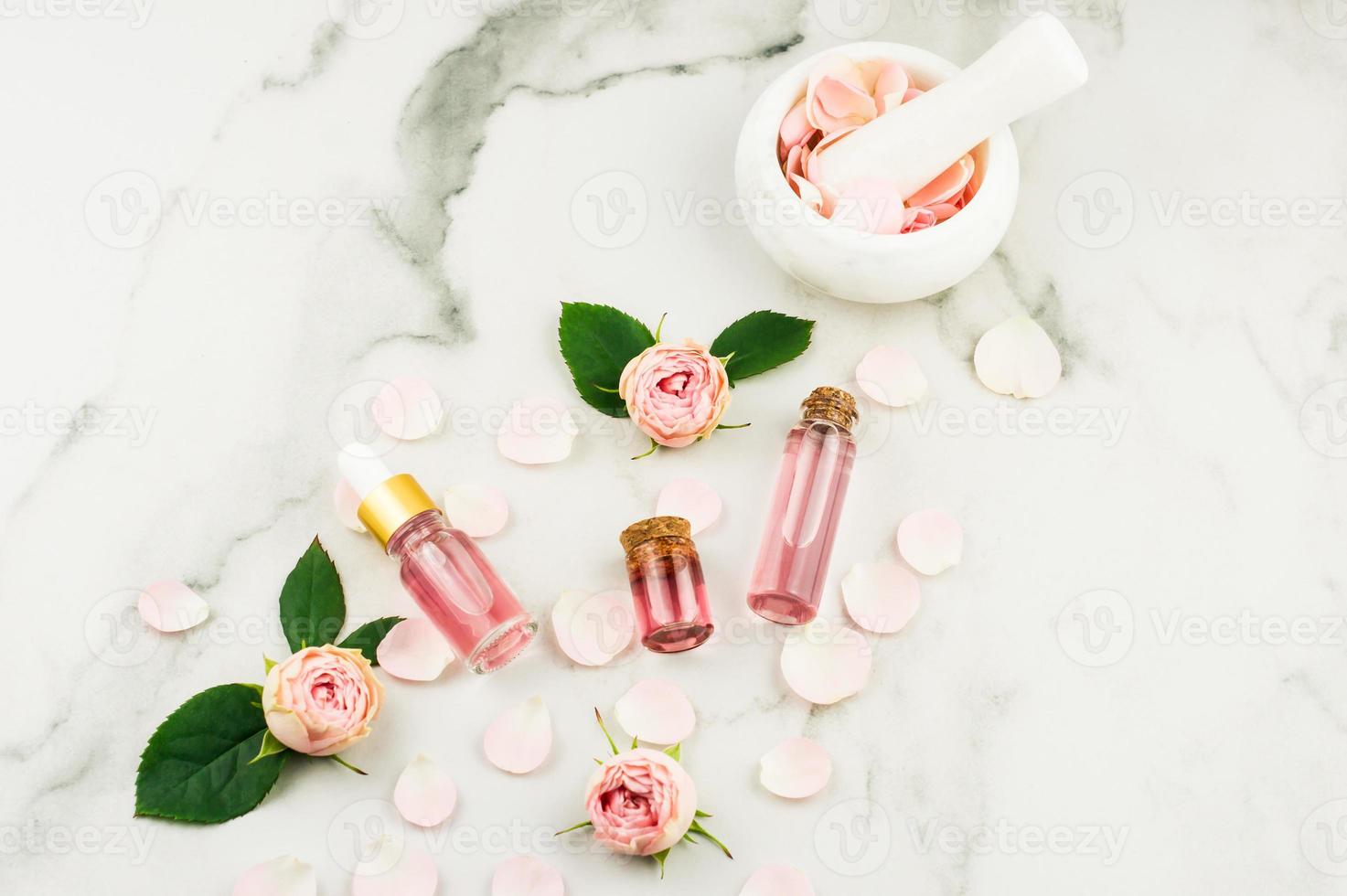 top view of cosmetic and glass bottles with cork lid with rose water and rose essential oil. white background. photo