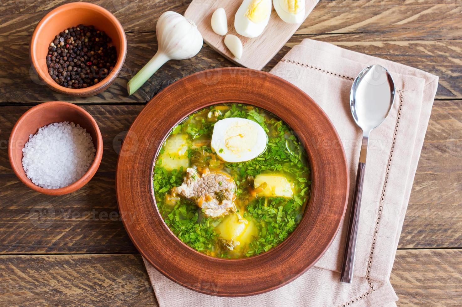 Sopa verde de acedera fresca con huevo cocido de pollo en caldo de res al vapor. comida dietetica vista superior.fondo de madera. foto