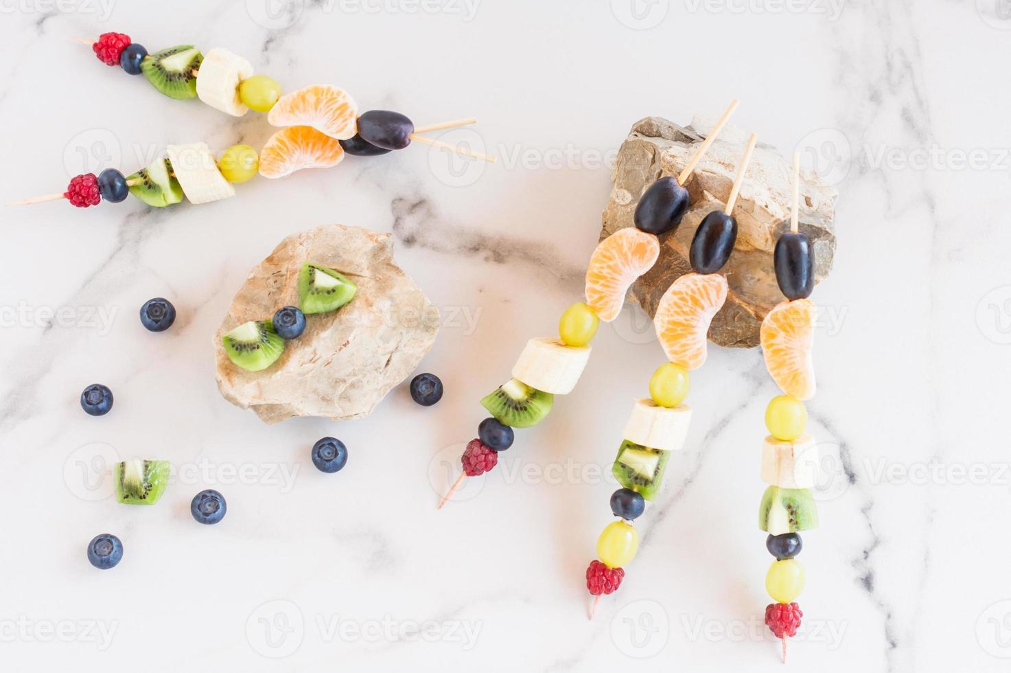 assortment of fruit canapes on stones, white marble background.vegetable vitamins. photo