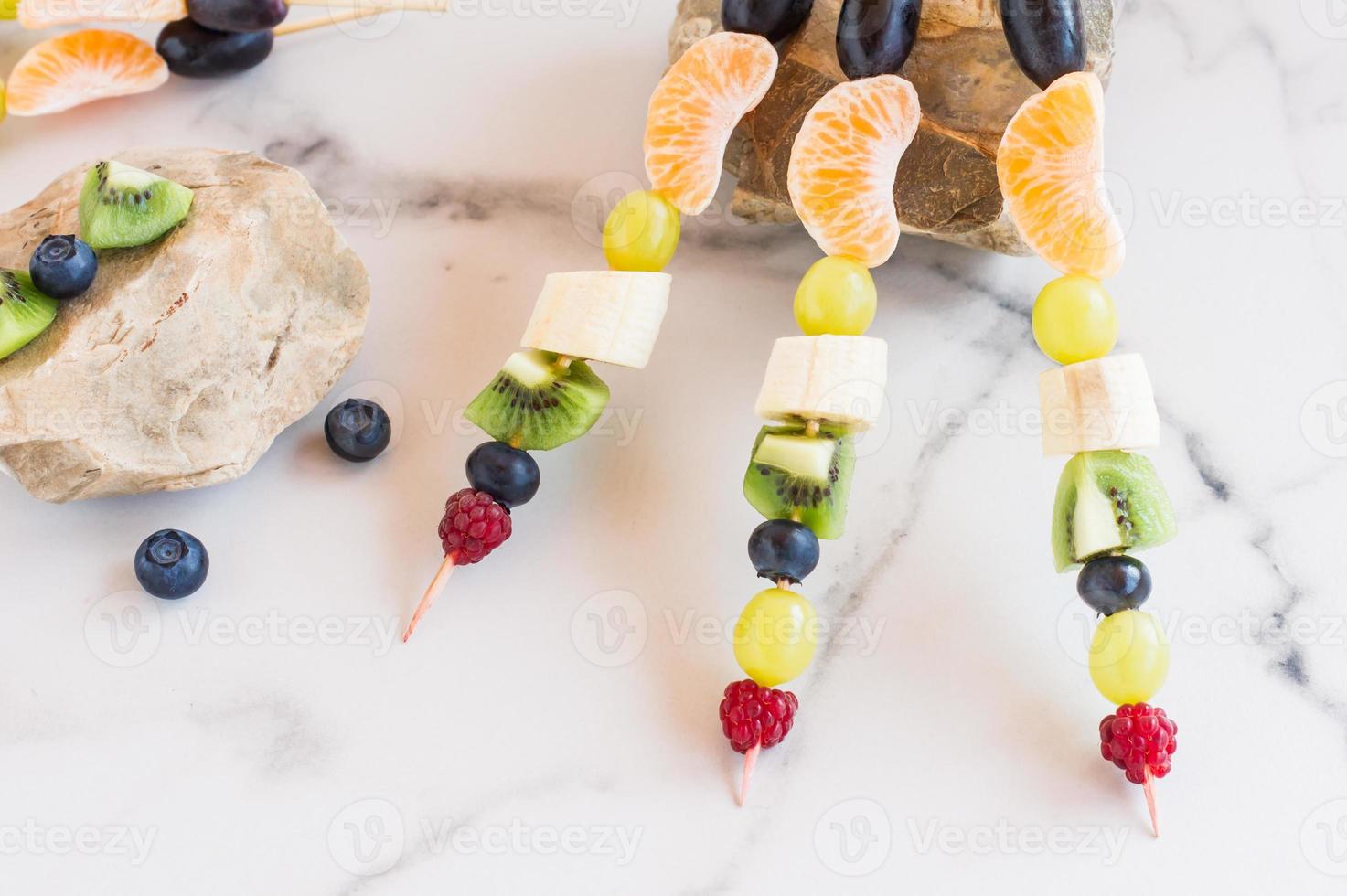 fresh fruit on skewers, composition on stones. summer dessert. photo