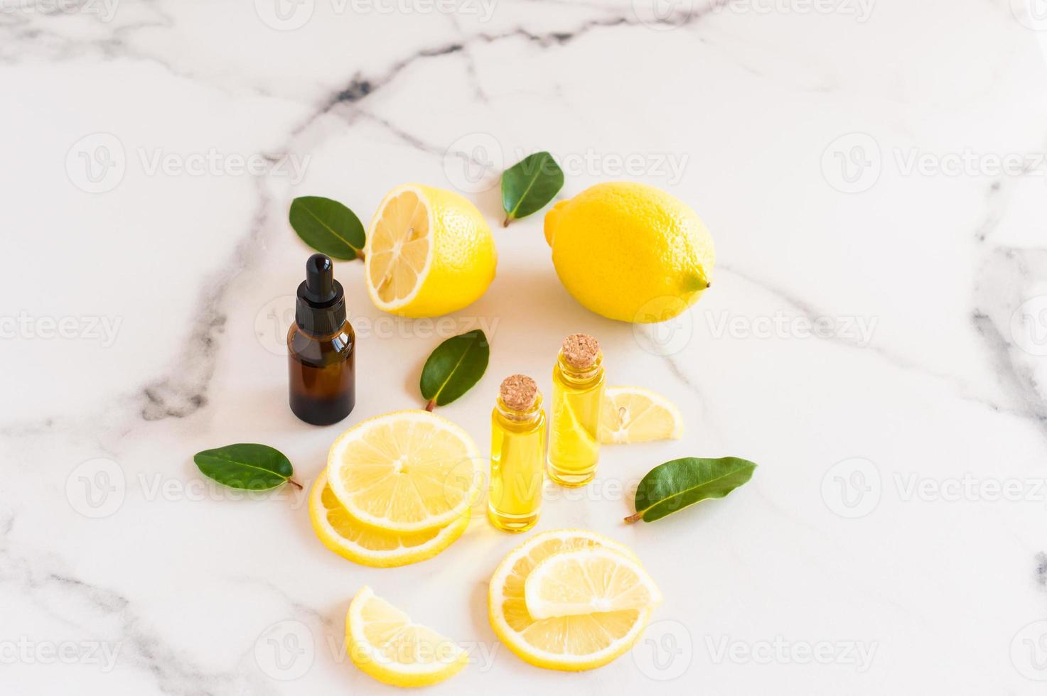 cosmetic lemon oil and citrus essential oil on a marble table. fruits of fresh lemon and melisa leaves. cosmetics of nature in glass bottles. photo