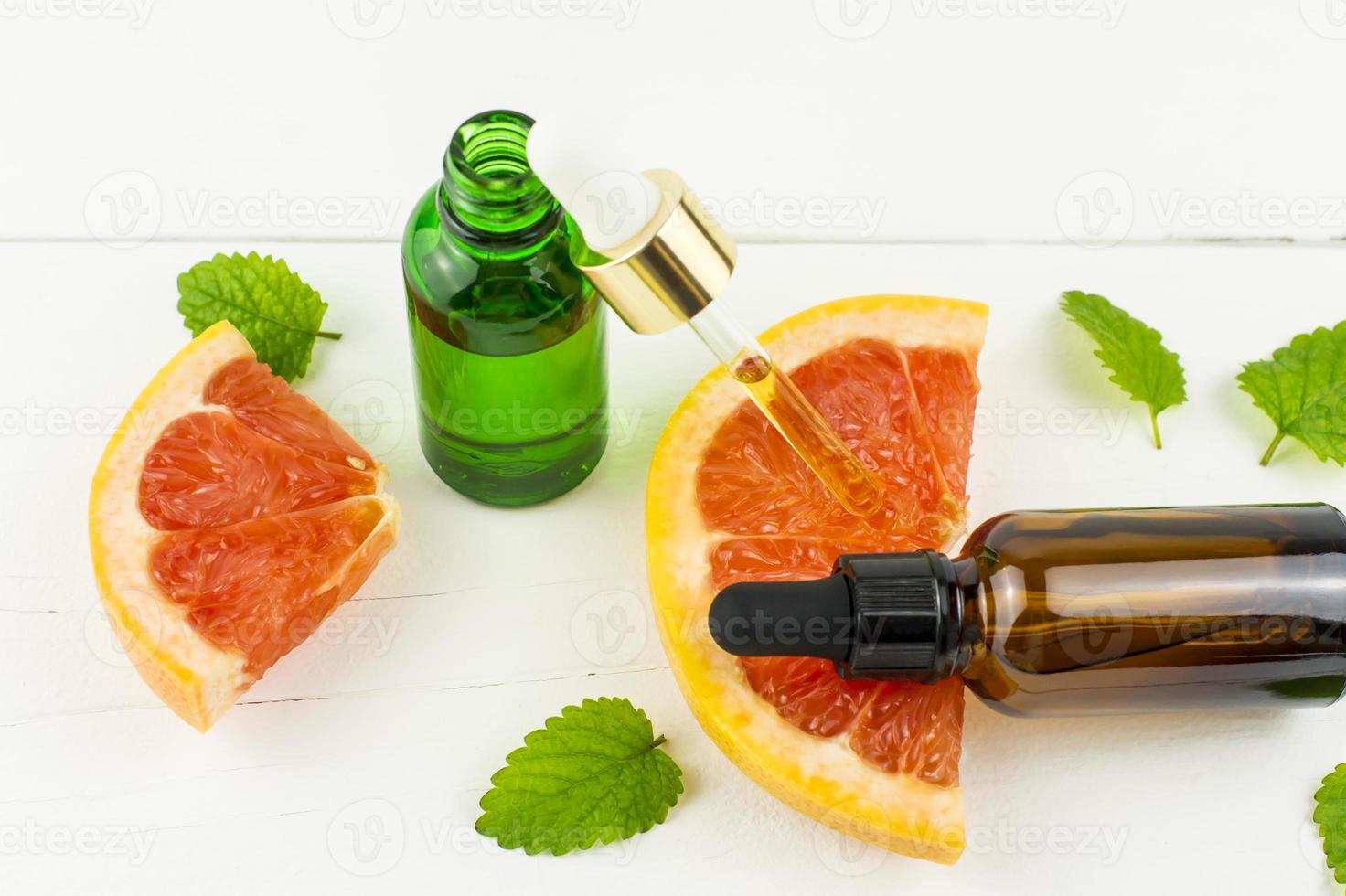 an open bottle with a cosmetic, grapefruit oil against the background of a sweet fruit. the concept of spa, aromatherapy, self-care. photo