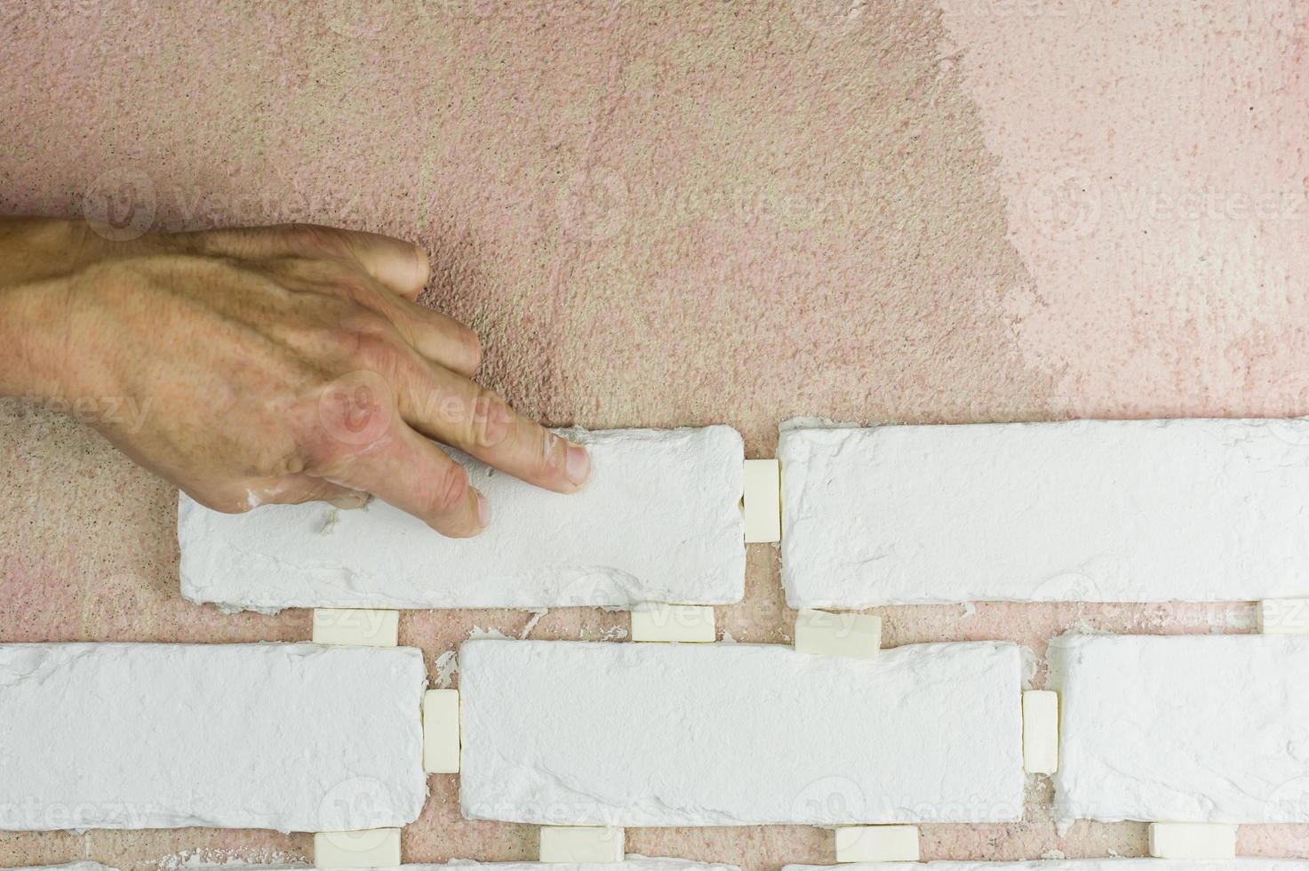 the employee's hand presses the decorative tiles against the finishing wall on the mortar. tile laying technology. photo