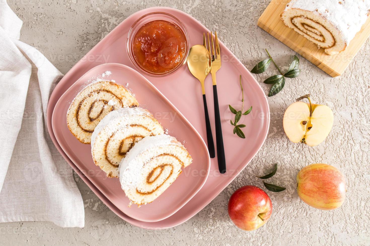 three pieces of homemade apple roll sponge cake are served on a pink ceramic plate and tray. snack dessert, snack. top view. gray background. photo