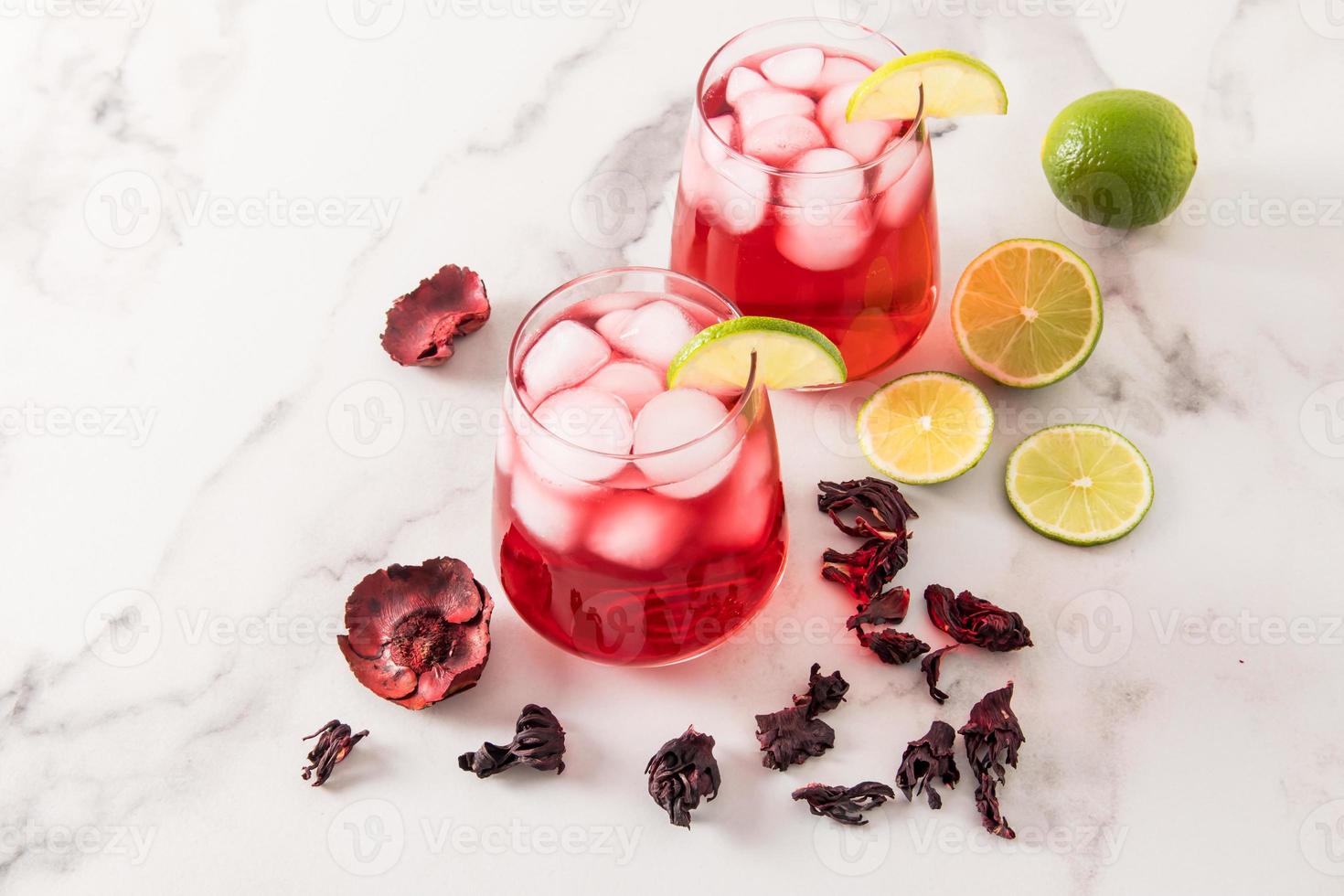 two glass glasses with hibiscus rose tea and with lots of ice, slices of lime. chilled thirsty drink in hot weather. marble background. photo