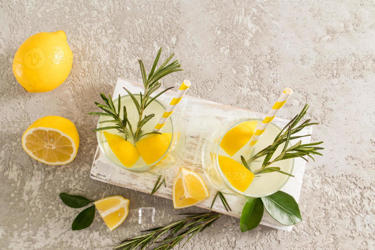 two glasses of homemade lemonade on a wooden white board and a concrete table. a healthy drink without additives and dyes. photo