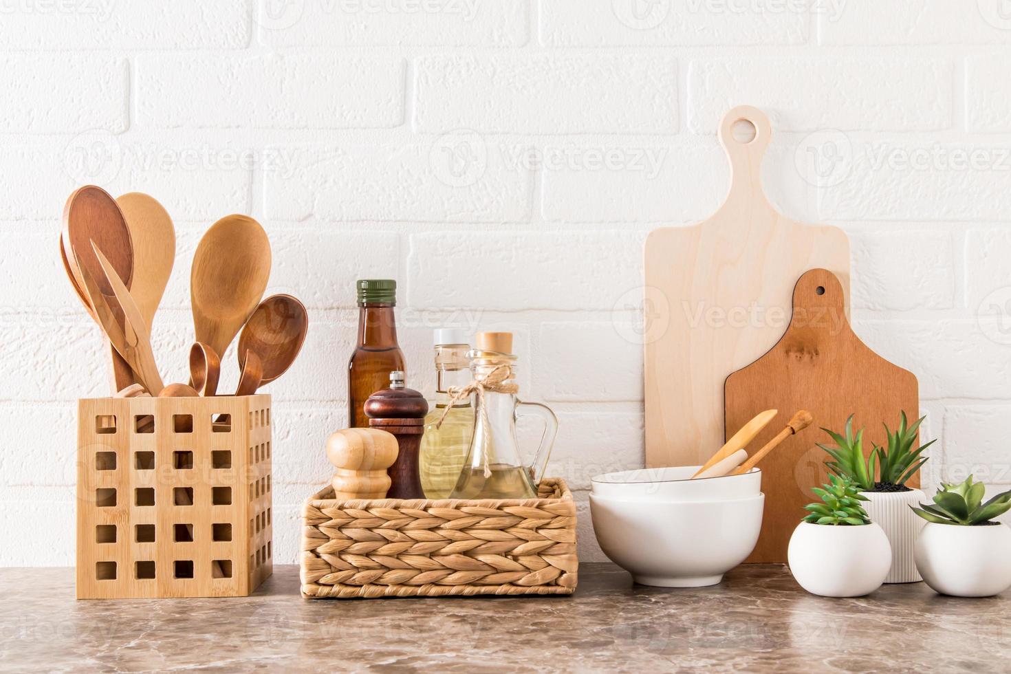 Stylish white kitchen background with kitchen utensils and green potted house plants on a marble countertop. photo
