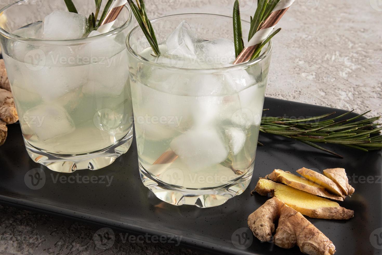 two glasses with a soft drink, homemade lemonade with ginger. close angle. gray background. photo
