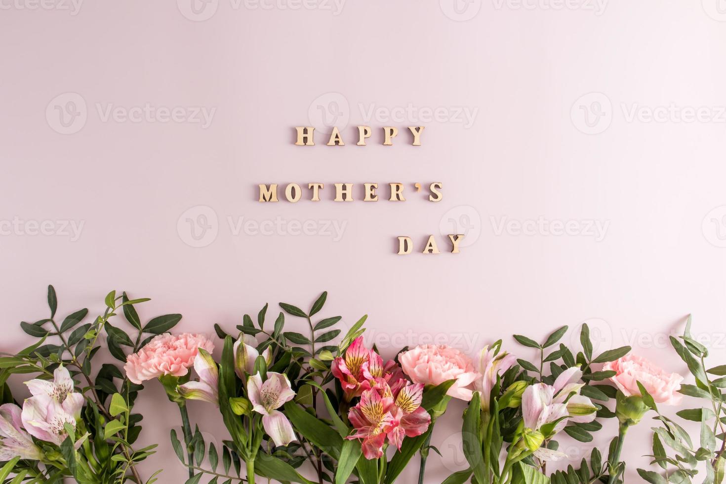 a festive composition, a poster, a mother's day card. a border of beautiful flowers on a purple background with an inscription. top view. flat lay. photo