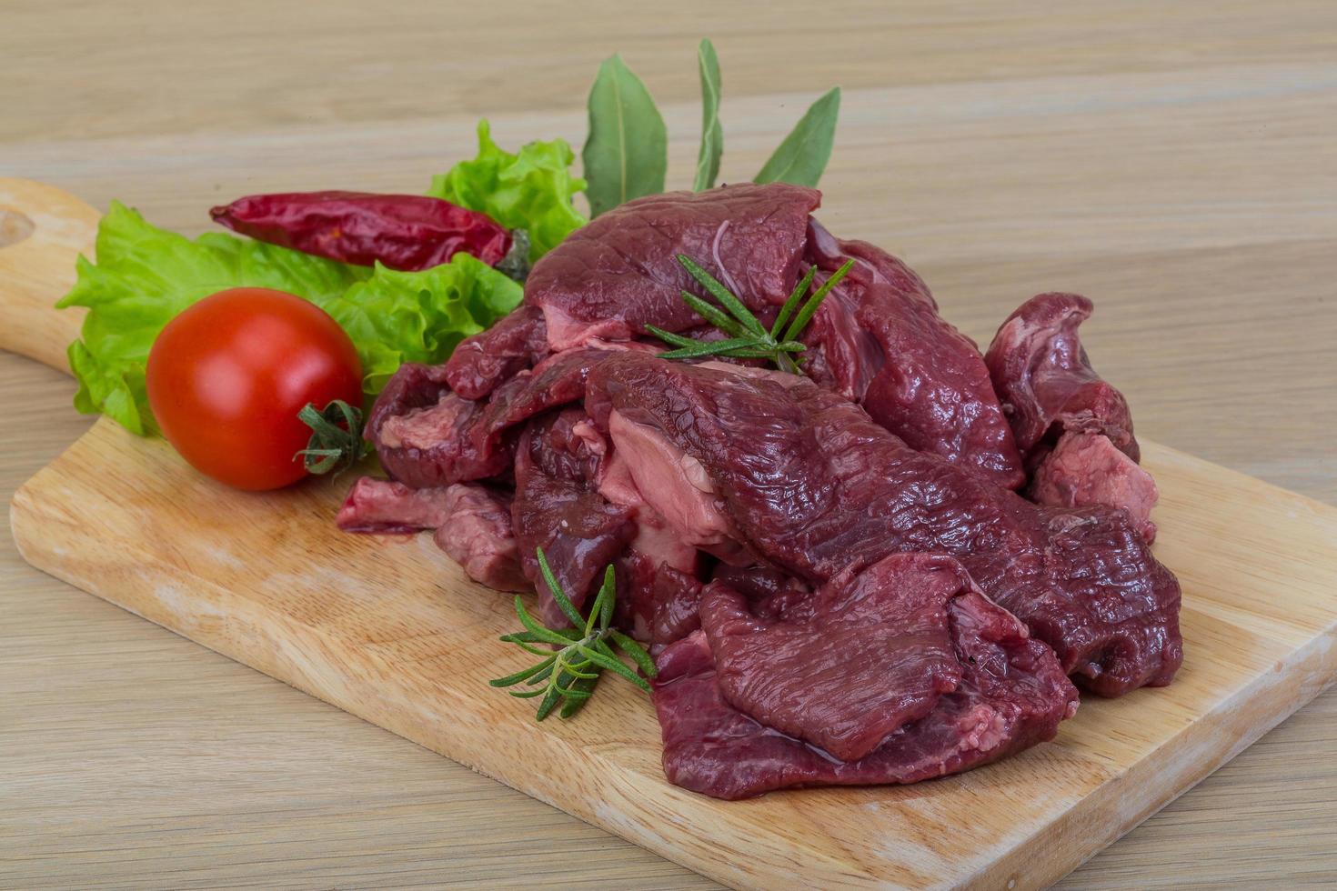 Raw venison on wooden board and wooden background photo