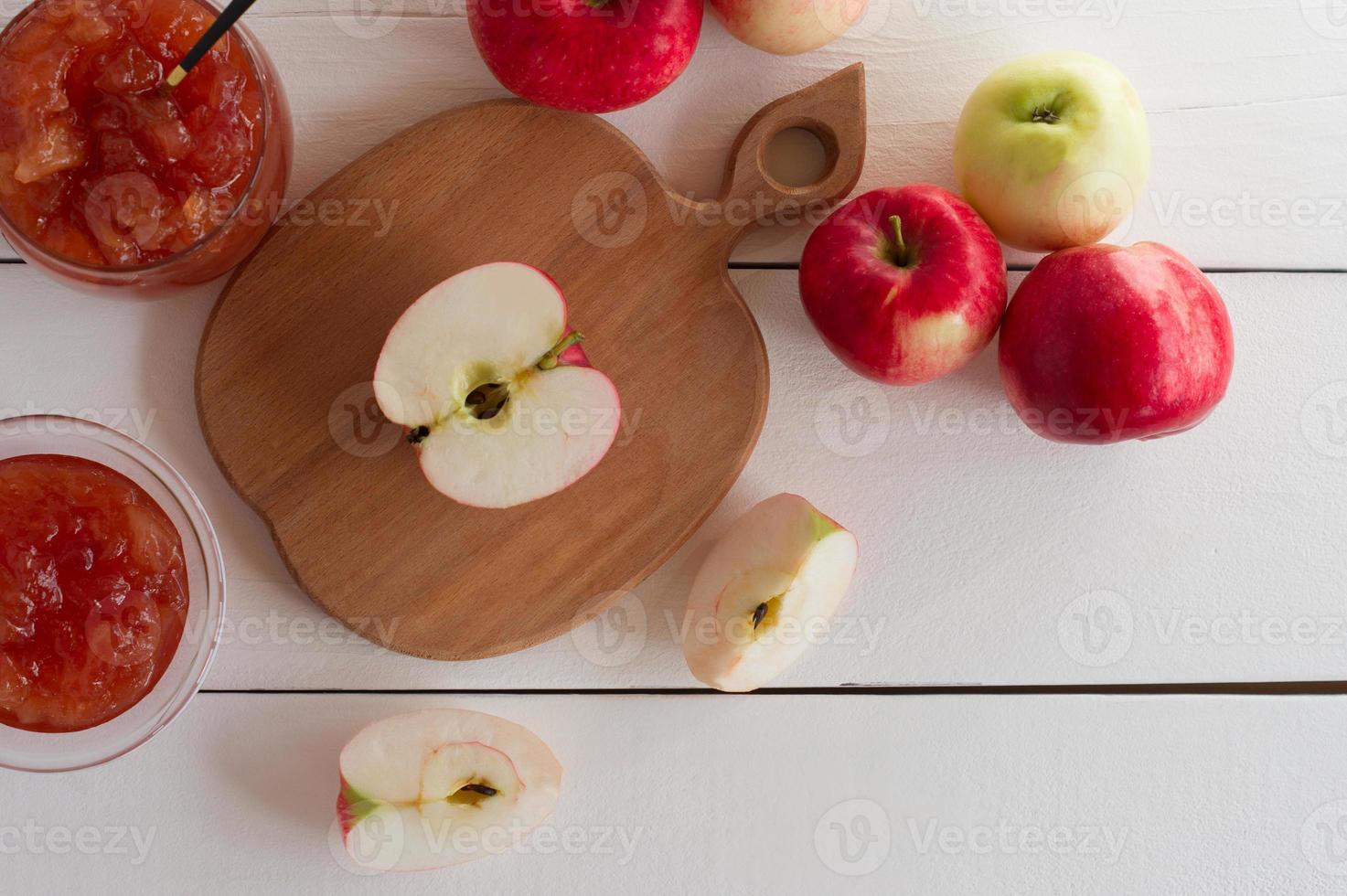 Fresh ripe red apples on a cutting board. Sweet apple jelly or jam in a glass bow. Dessert for healthy eating photo