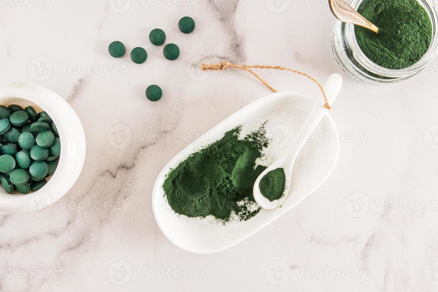 Organic green spirulina powder and green algae tablets in a white bowl and  spoon on a marble table. top view. food source of vitamin protein. 12875761  Stock Photo at Vecteezy