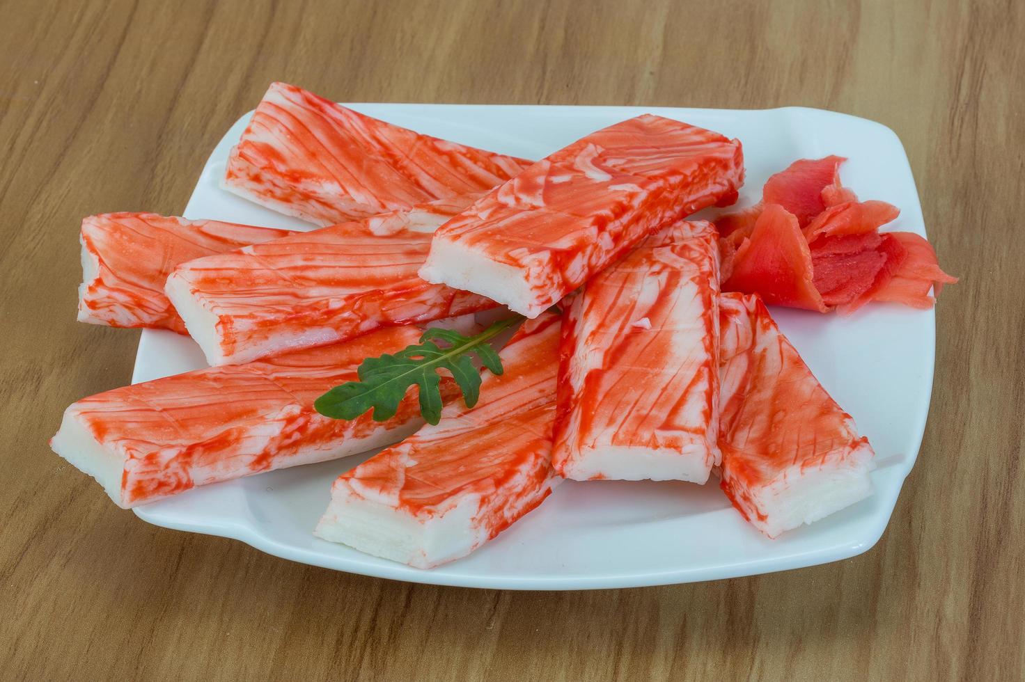 palitos de cangrejo en el plato y fondo de madera foto