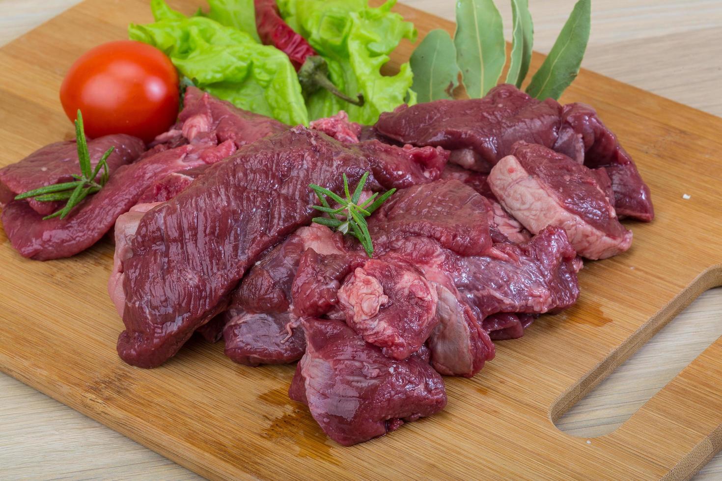 Raw venison on wooden board and wooden background photo