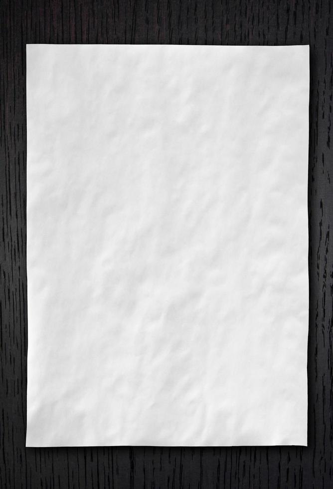 Wrinkled White paper on dark wood background photo