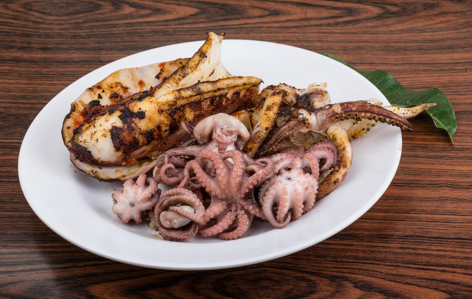 Boiled octopus on the plate and wooden background photo