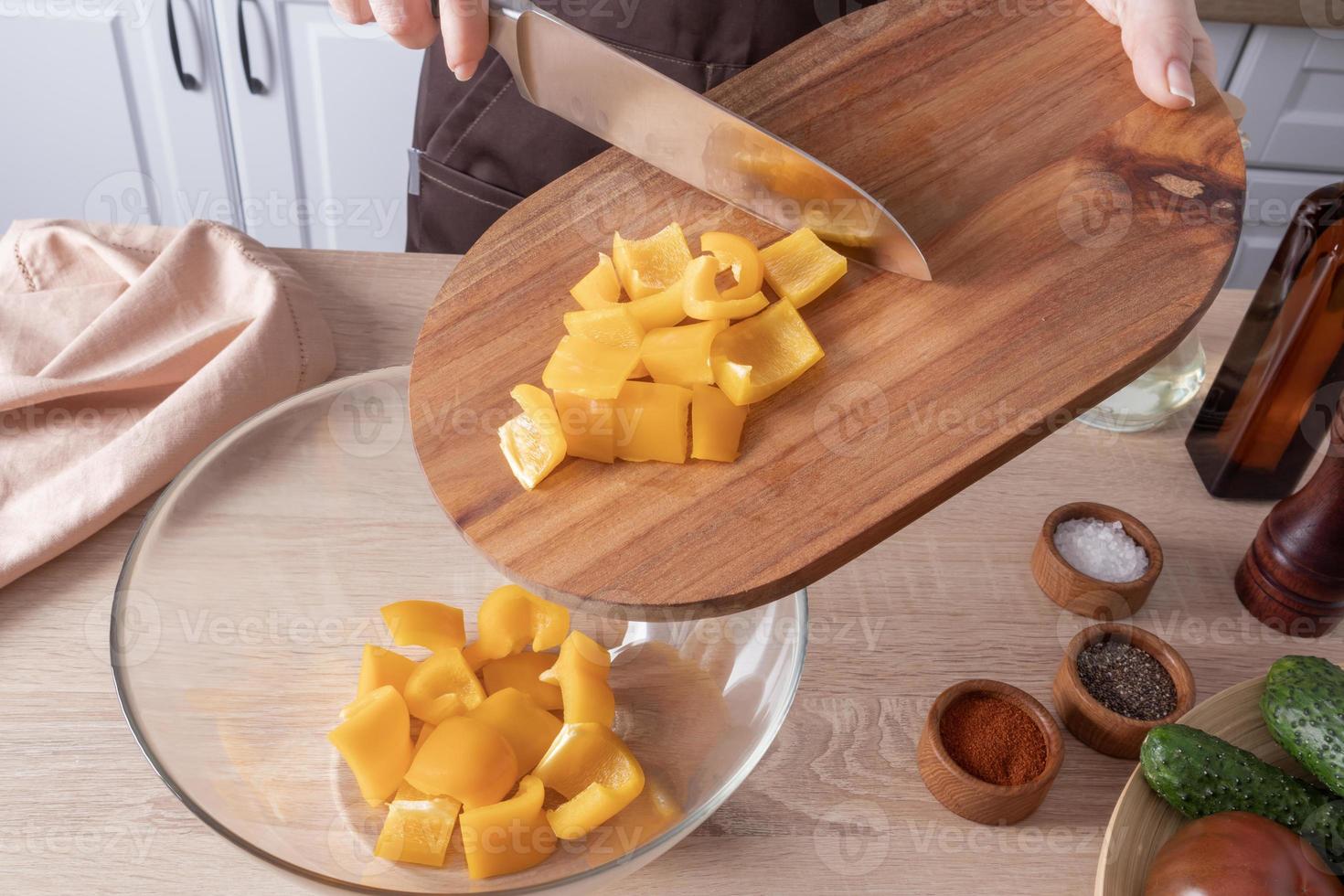 close-up of a cutting board with chopped pepper. the process of pouring it into a salad bowl. the concept of healthy food. photo