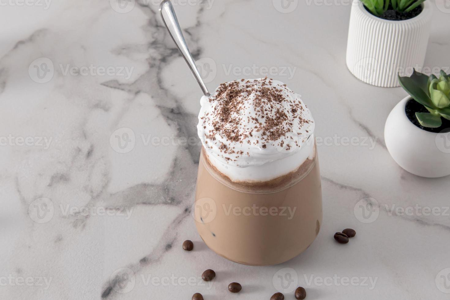 un gran vaso de café con leche o una bebida de chocolate sobre una mesa de mármol blanco. crema batida y canela para mejorar el sabor. postre. foto