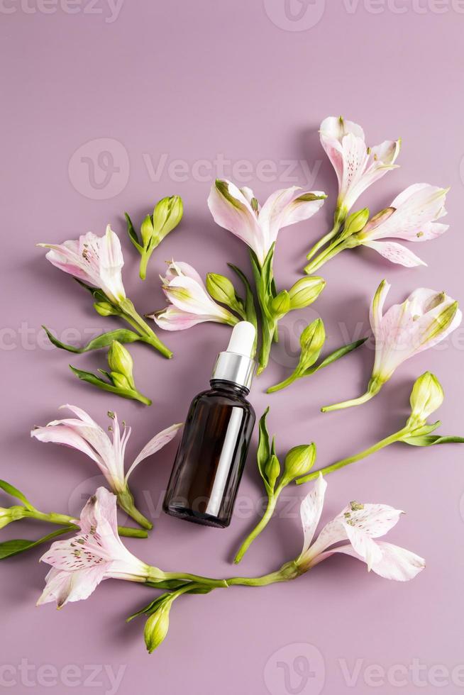 vertical floral background with cosmetic bubble with pipette with essential oil, serum for self-care. Anievost care. photo