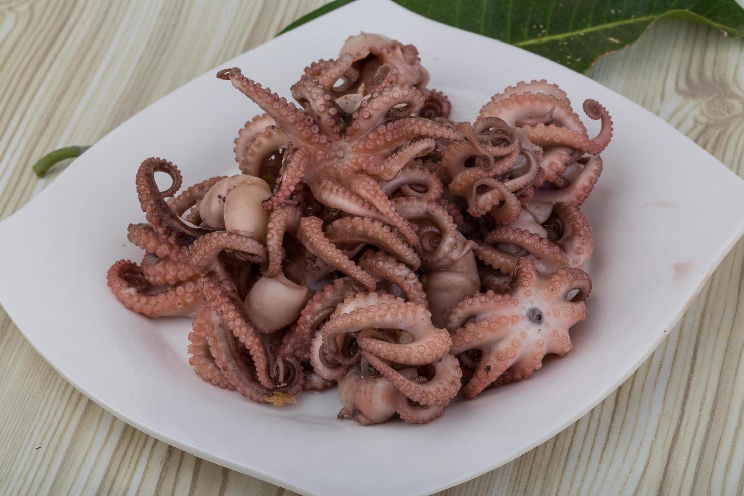 Boiled octopus on the plate and wooden background photo