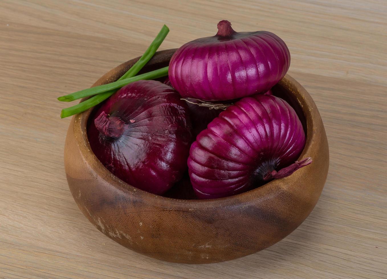 Violet onion in a bowl on wooden background photo