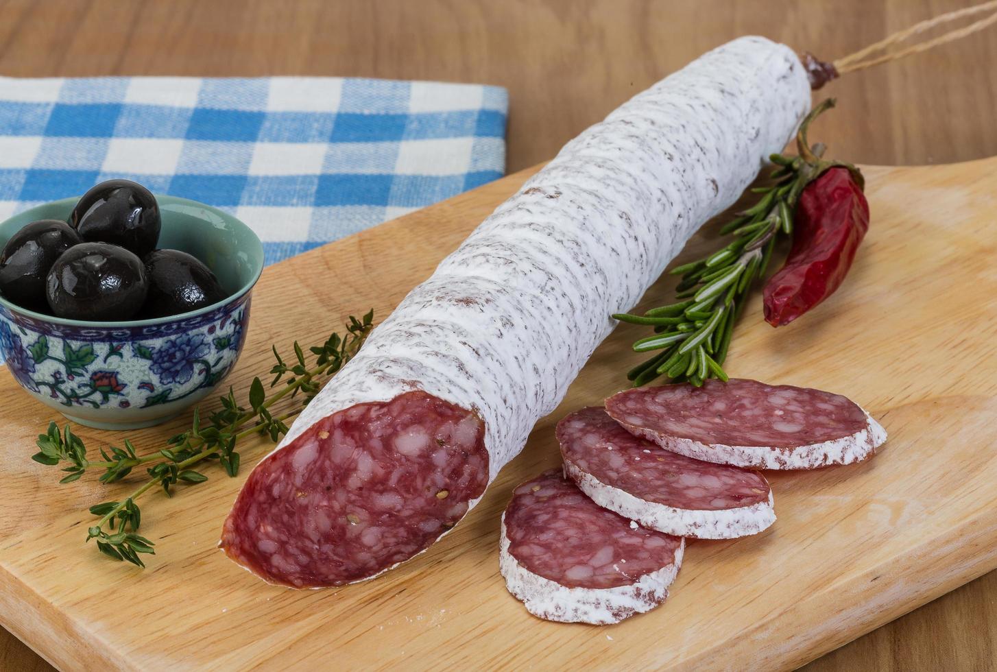 Fuet sausage on wooden board and wooden background photo