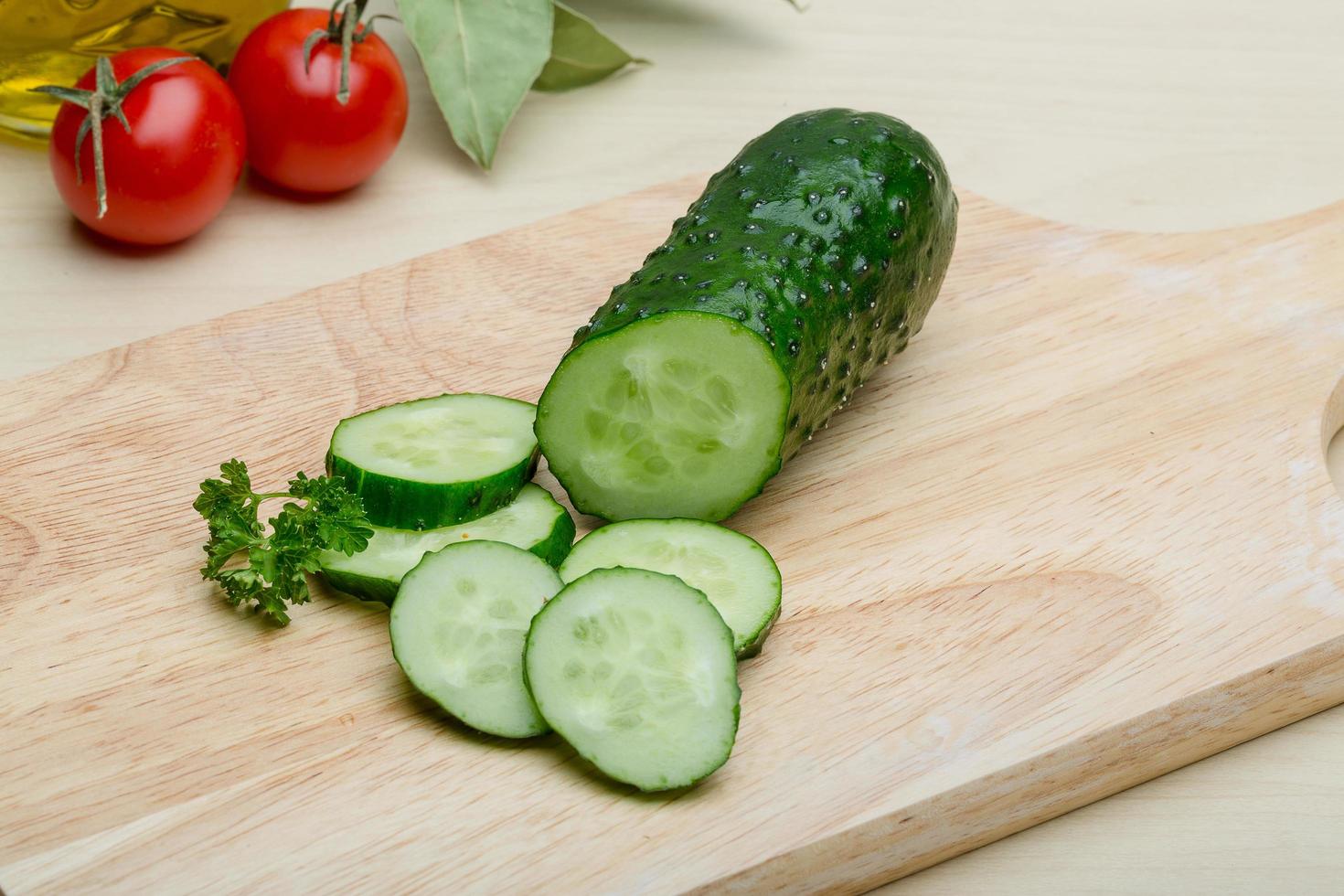 Sliced cucumber on wooden board and wooden background photo