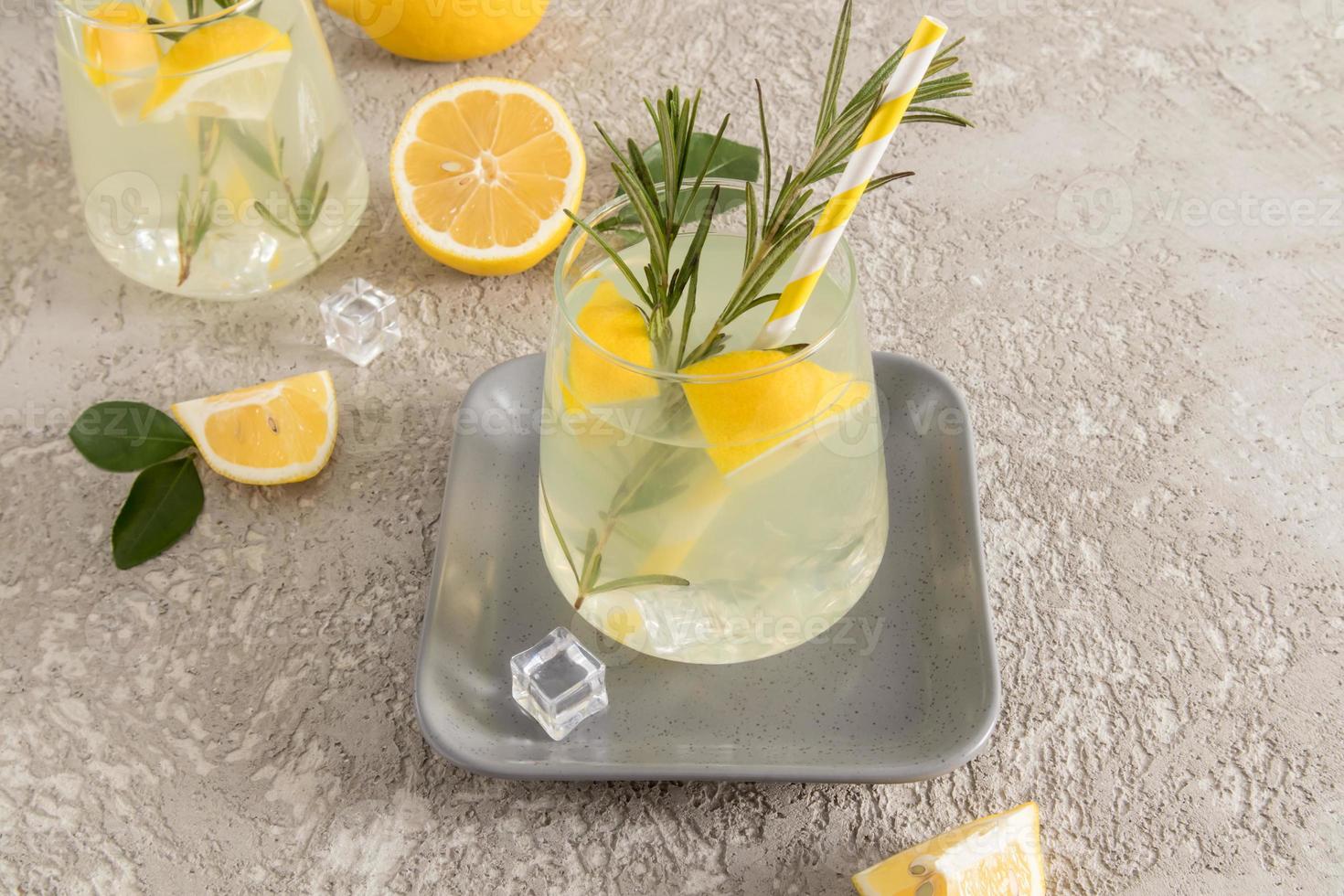 a glass of chilled homemade lemonade with rosemary to improve the taste. a healthy vitamin drink. vitamin C. concrete table. close angle. photo