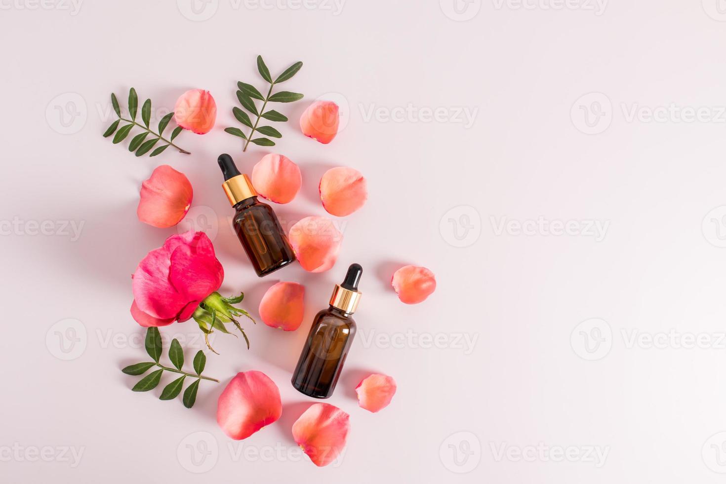 two cosmetic bottles with a dropper pipette against the background of the petals of a red tea rose. natural cosmetics. additional skin care. photo