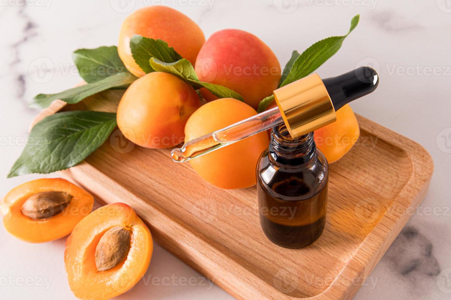 an open bottle with a dropper of cosmetic organic oil apricot on a tray wooden of fruity for face and body skin care. relaxation. phytotherapy. photo