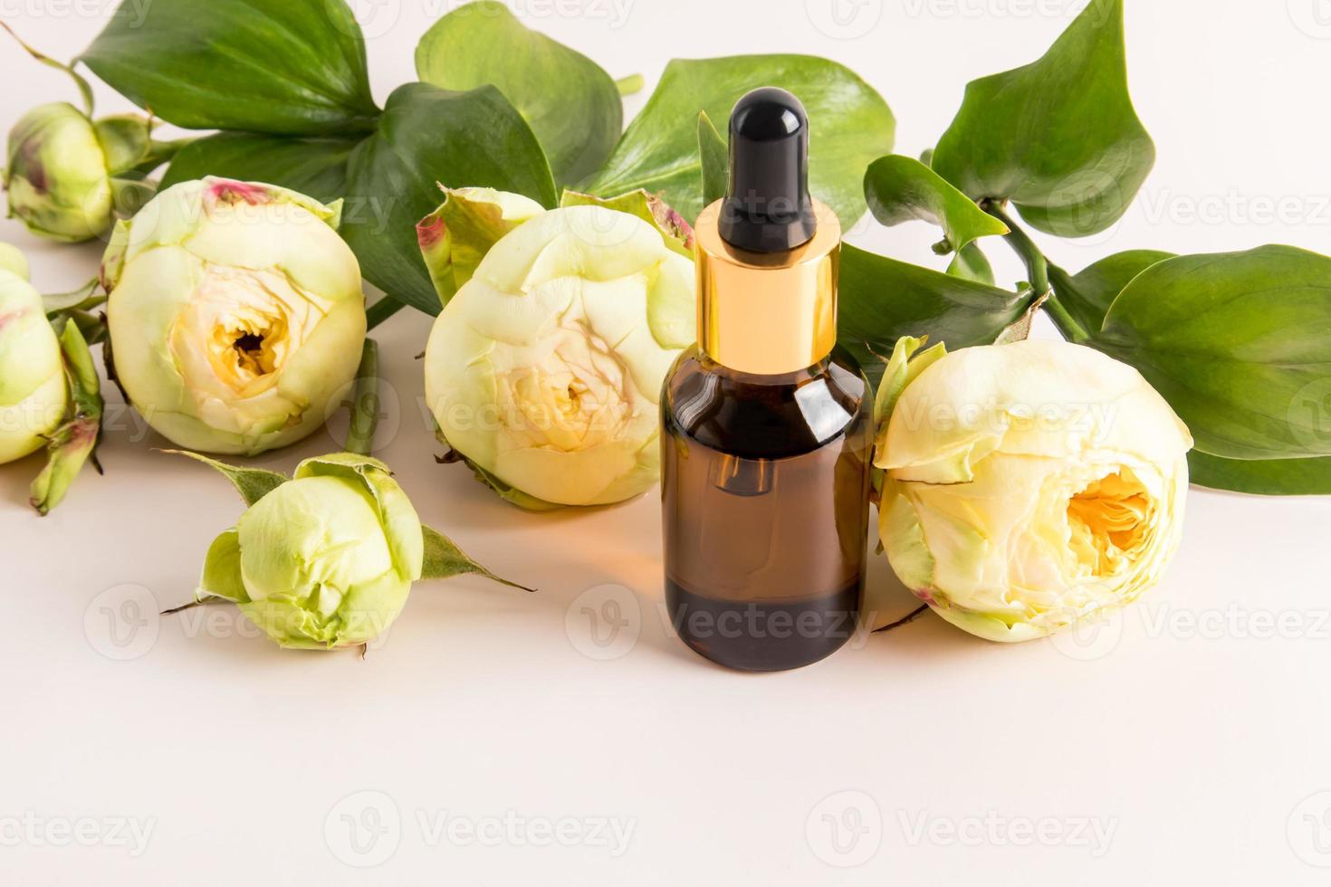 moisturizing serum in a glass brown bottle with a dropper pipette against the background of yellow peony buds. natural cosmetics. photo