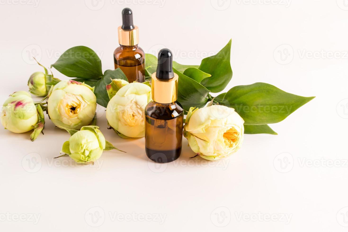 nature cosmetics in glass bottles with a pipette and beautiful bbctons of peonies on a pastel background. natural organic product for self-care. photo