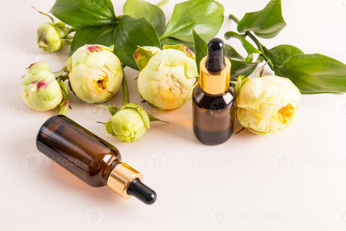 composition of bottles of dark glass with cosmetic, medical product. bottles with a pipette against the backdrop of beautiful peonies. photo