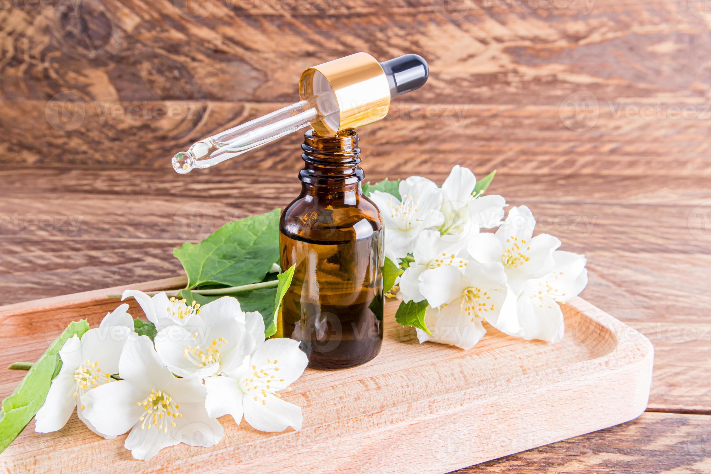 an open glass bottle of organic jasmine oil stands on a wooden tray
