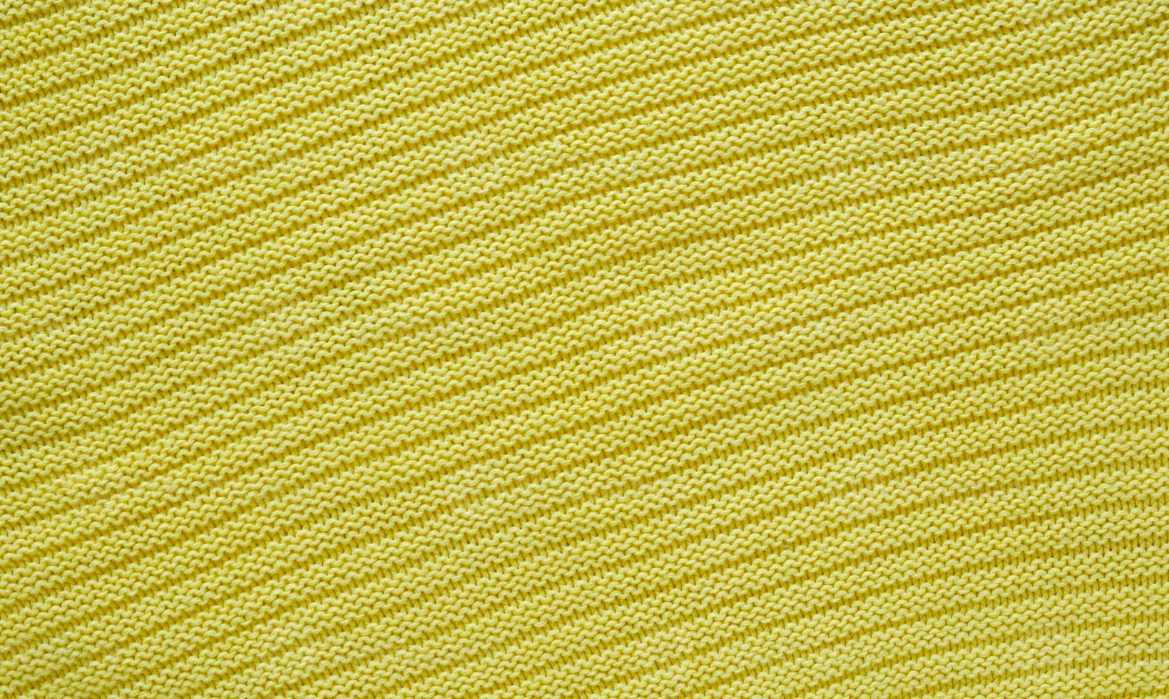 Texture of smooth knitted yellow sweater with pattern. Top view, close-up. Handmade knitting wool or cotton fabric texture. Background of knitting patterns. photo
