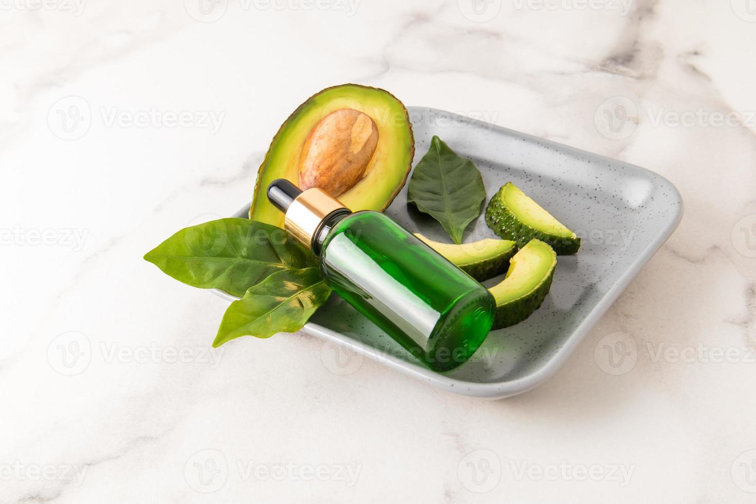 natural avocado oil in a cosmetic bottle with a pipette against the background of a ripe juicy fruit. deep moisturizing. photo