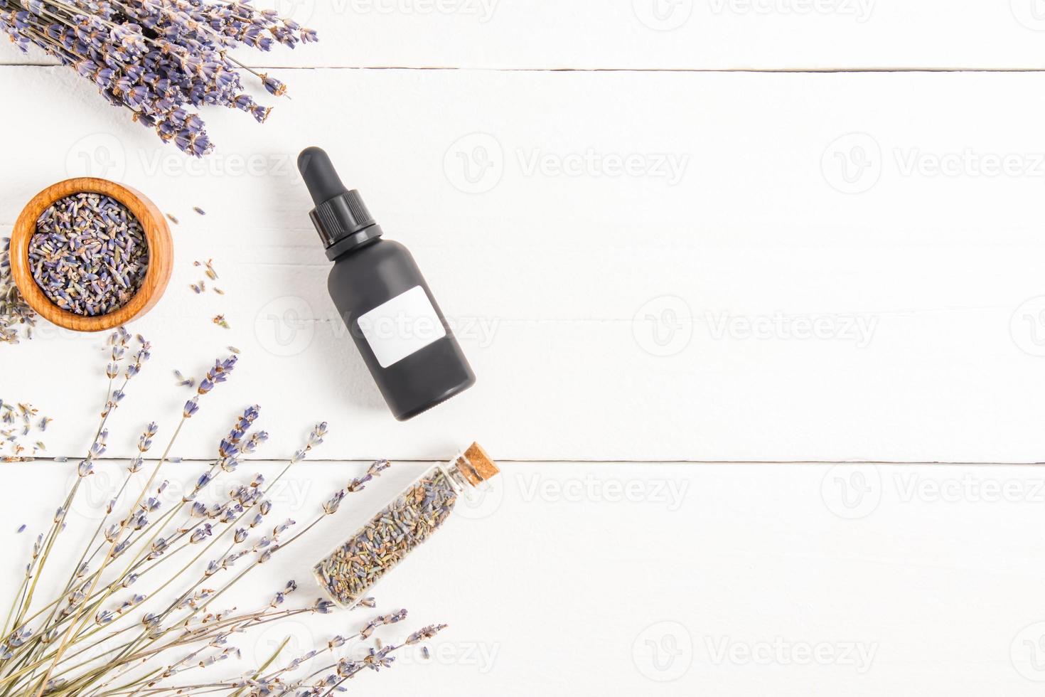 cosmetic bottle of frosted black glass with oil or lavender serum on a white background of wooden boards. unbranded. mosk-up. photo