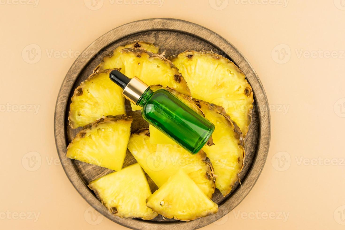 face serum with pineapple extract or moisturizing cosmetic oil on a wooden tray with juicy fruit slices. top view. photo