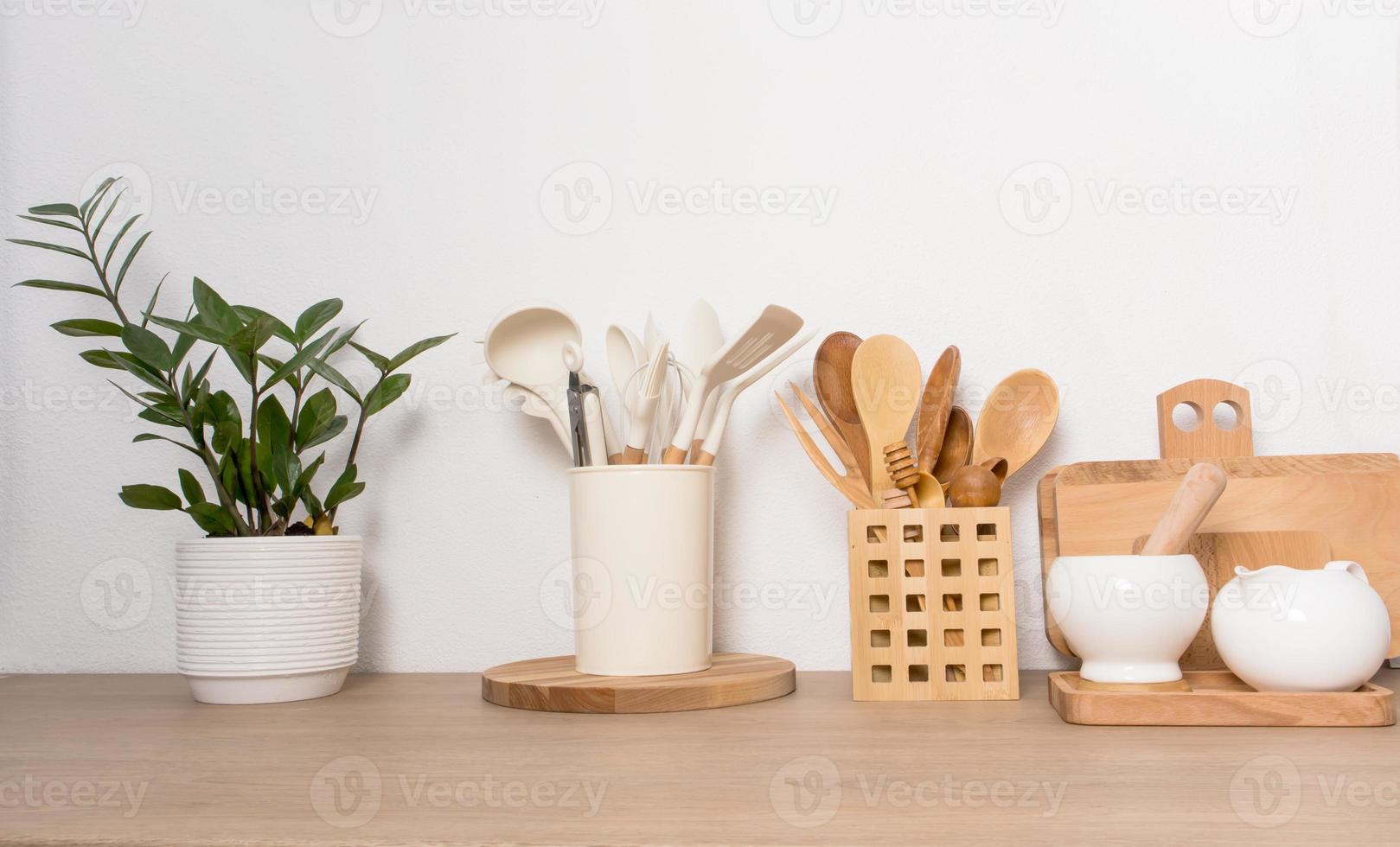 encimera de madera de cocina con varios utensilios para cocinar en casa. flor verde en una vasija de cerámica. foto