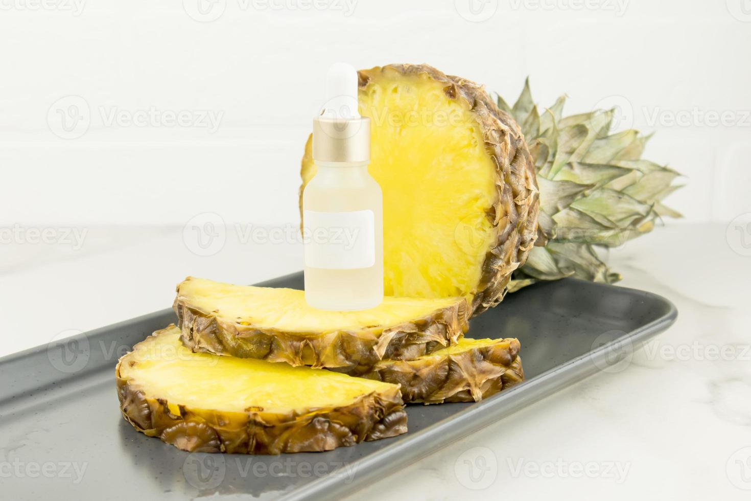 a brightening serum with pineapple extract in a cosmetic white bottle with a pipette stands onpineapple slices. natural cosmetics. Unbranded mock-up. photo